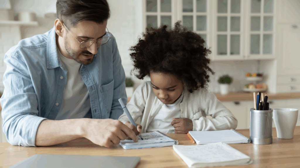 Father and daughter engaged in educational activity at kitchen table, illustrating family bonding and support in the context of adoption.